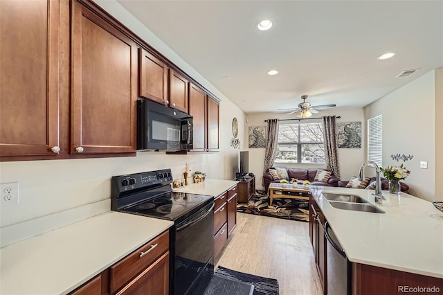kitchen with light wood finished floors, a sink, visible vents, light countertops, and black appliances