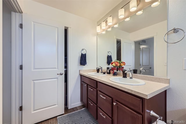 full bathroom with visible vents, wood finished floors, a sink, and double vanity