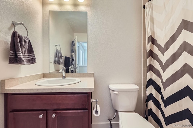 full bathroom with toilet, a textured wall, vanity, and a shower with shower curtain