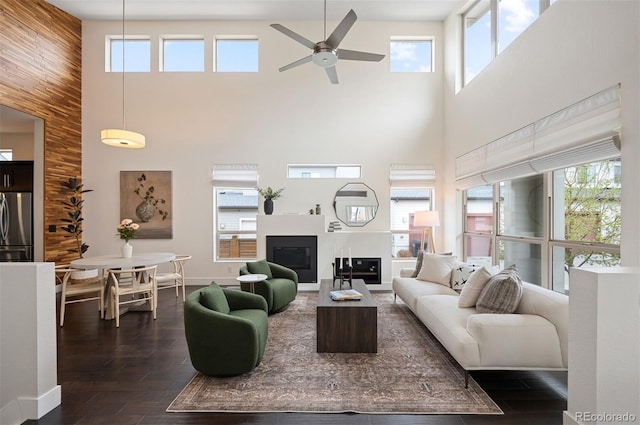 5050 Akron St, Denver, CO 80238 - living room featuring a towering ceiling, a ceiling fan, a glass covered fireplace, dark wood-type flooring, and baseboards