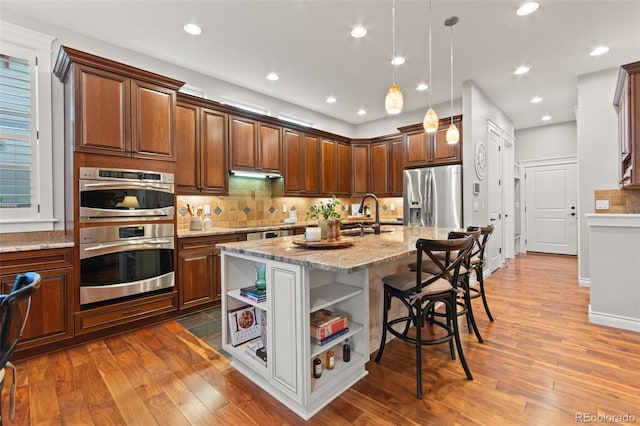 24906 E Geddes Cir, Aurora, CO 80016 - kitchen featuring appliances with stainless steel finishes, open shelves, a breakfast bar, light stone counters, and tasteful backsplash