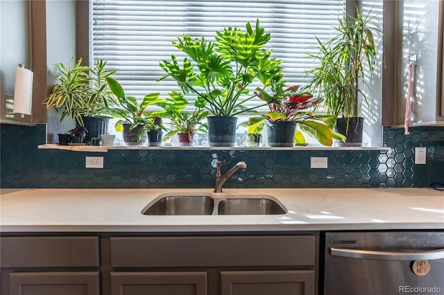 kitchen featuring light countertops, stainless steel dishwasher, a sink, and a healthy amount of sunlight