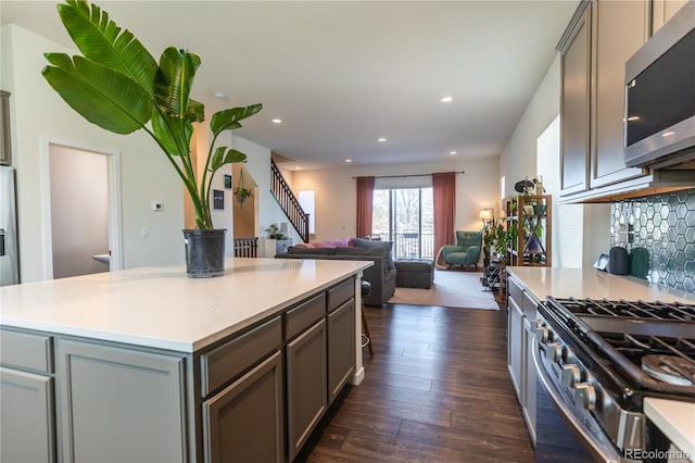 kitchen with stainless steel appliances, open floor plan, light countertops, gray cabinets, and decorative backsplash