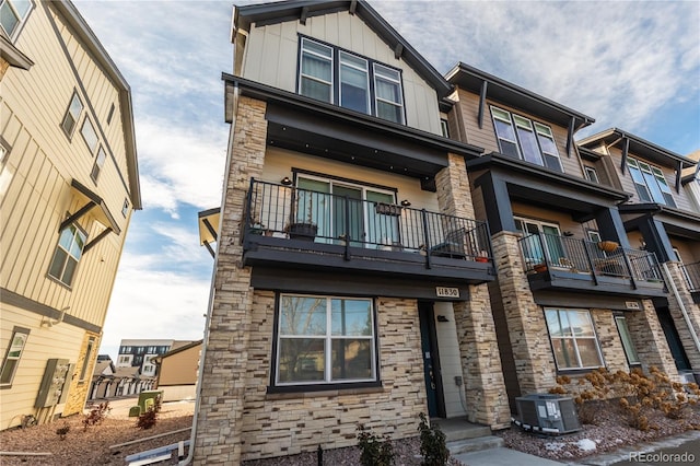 townhome / multi-family property featuring board and batten siding, stone siding, and central AC unit