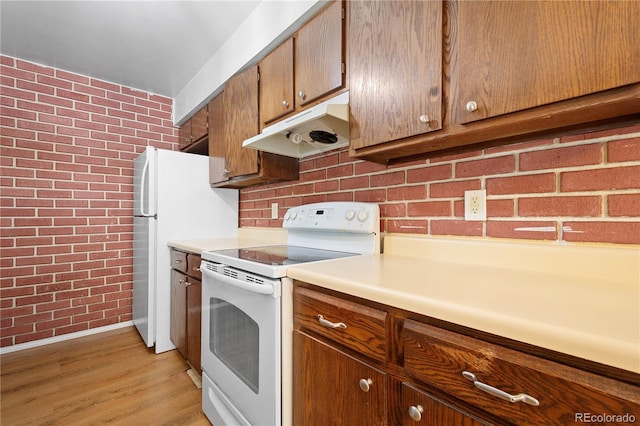 kitchen with brick wall, white appliances, and light wood-type flooring