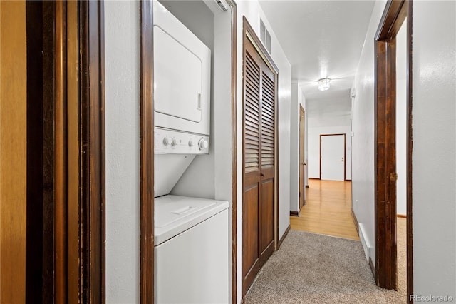 laundry room with light colored carpet and stacked washer / drying machine