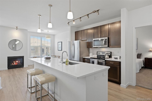 17353 Wilde Ave Unit 308, Parker, CO 80134 - kitchen with appliances with stainless steel finishes, dark brown cabinetry, a breakfast bar, and light wood-type flooring