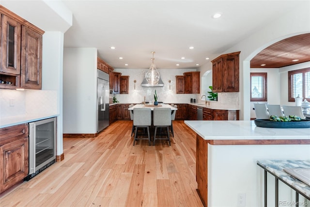 kitchen featuring a breakfast bar, a center island, light hardwood / wood-style flooring, stainless steel appliances, and beverage cooler