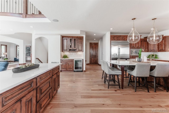 kitchen with built in appliances, a breakfast bar, wine cooler, and light wood-type flooring