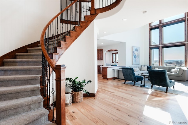 stairway with wood-type flooring and a high ceiling