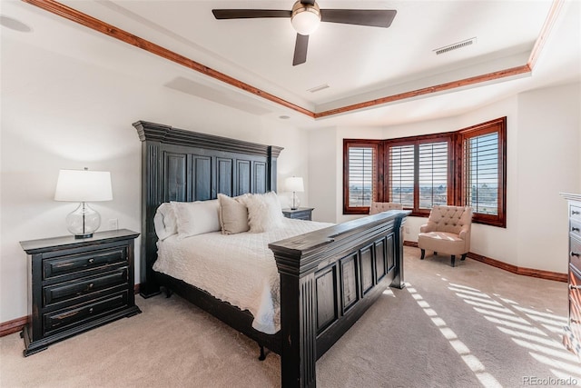 bedroom featuring light carpet, a tray ceiling, ceiling fan, and ornamental molding