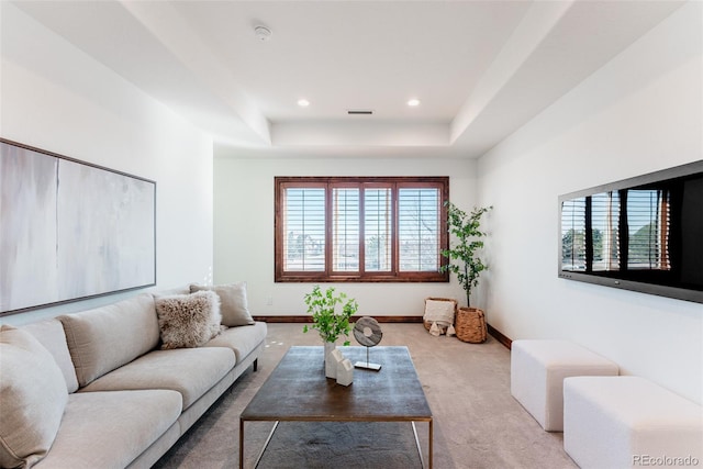 living room with a raised ceiling, a wealth of natural light, and light colored carpet