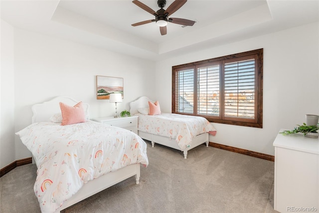 carpeted bedroom featuring ceiling fan and a tray ceiling