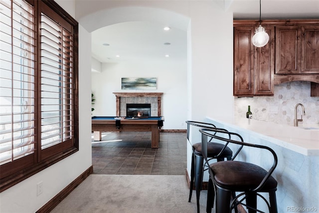 kitchen with a kitchen bar, dark colored carpet, pendant lighting, a fireplace, and pool table