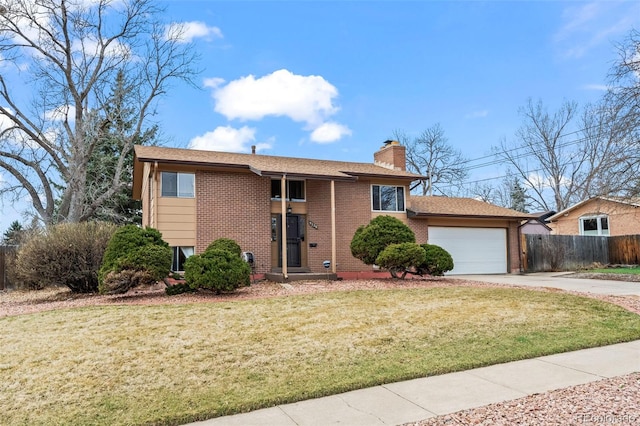 split foyer home featuring fence, a garage, brick siding, a front lawn, and driveway