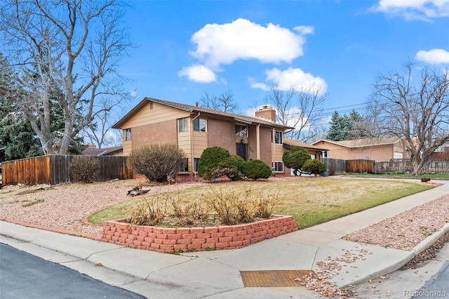 view of front of property with brick siding, fence, a chimney, and a front lawn
