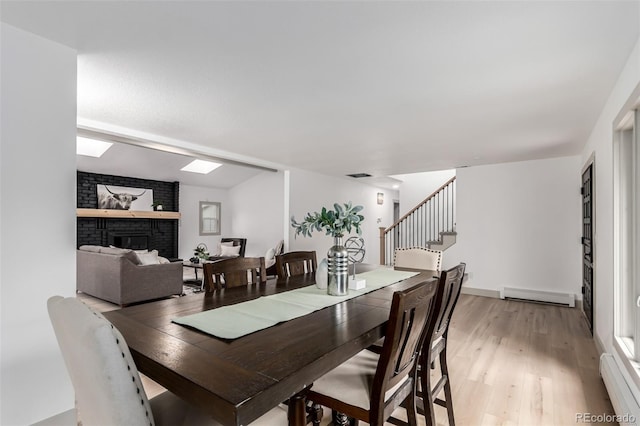 dining area with light hardwood / wood-style floors, a baseboard heating unit, and a fireplace