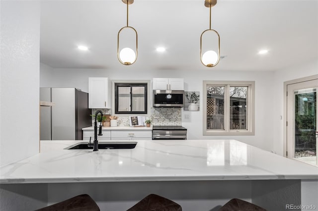 kitchen with appliances with stainless steel finishes, kitchen peninsula, pendant lighting, and white cabinets