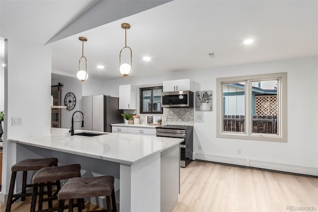 kitchen with white cabinetry, kitchen peninsula, stainless steel appliances, a barn door, and pendant lighting