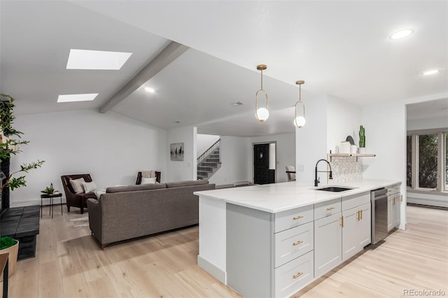 kitchen featuring light wood-type flooring, light stone countertops, decorative light fixtures, sink, and white cabinetry