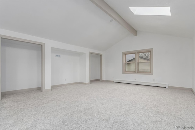 interior space featuring vaulted ceiling with skylight, baseboard heating, and carpet