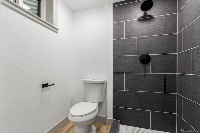 bathroom featuring tiled shower, wood-type flooring, and toilet