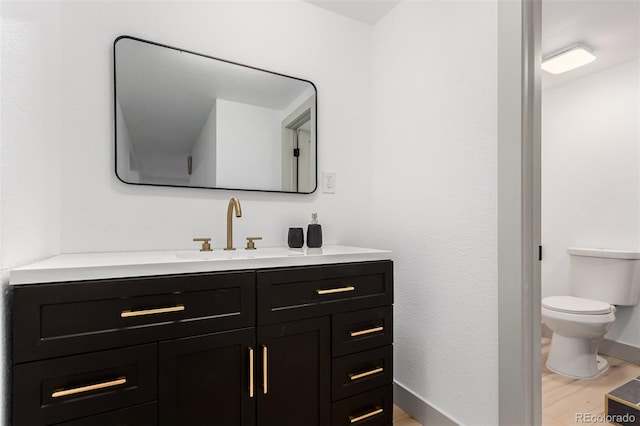 bathroom with toilet, wood-type flooring, and vanity