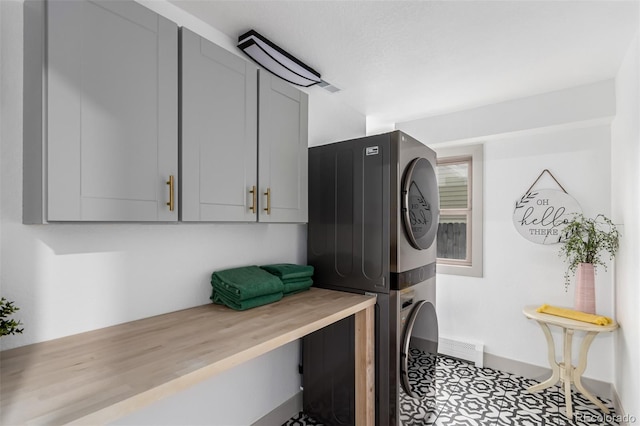 clothes washing area with cabinets and stacked washer and clothes dryer