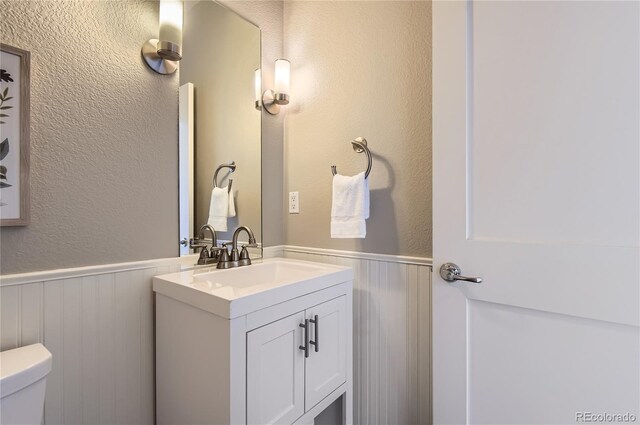 2700 E Louisiana Ave Unit 203, Denver, CO 80210 - bathroom featuring wainscoting, vanity, toilet, and a textured wall