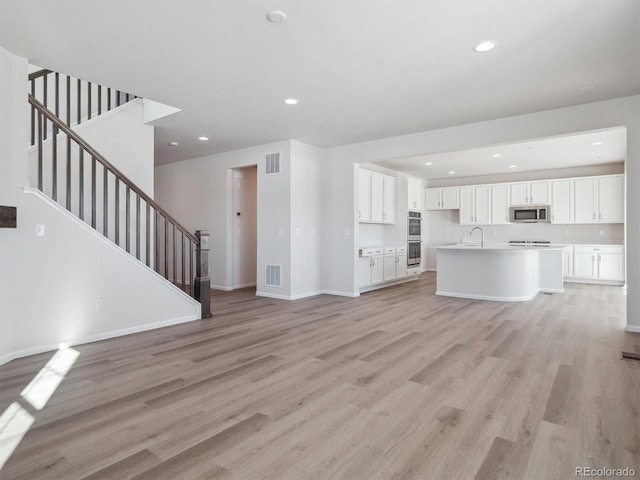 unfurnished living room featuring light hardwood / wood-style floors and sink