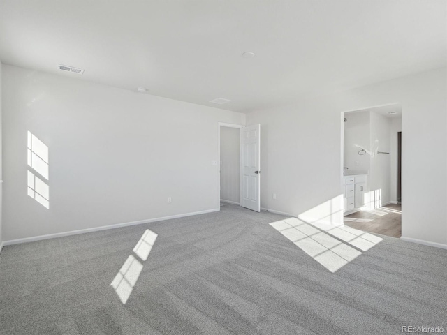 unfurnished bedroom featuring ensuite bathroom and light carpet