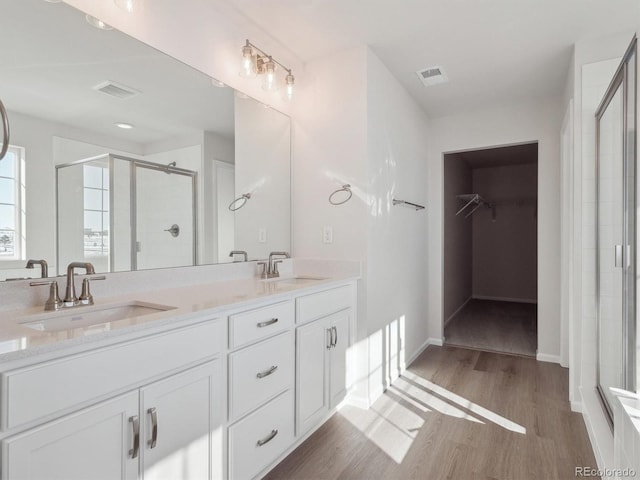 bathroom with hardwood / wood-style floors, vanity, and a shower with door