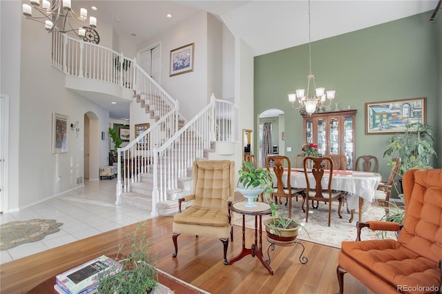 living room with a chandelier, high vaulted ceiling, and light hardwood / wood-style flooring