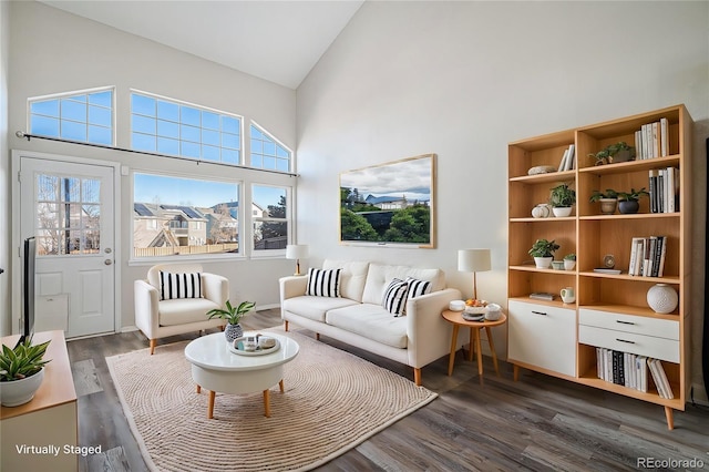 living room featuring dark wood-type flooring, high vaulted ceiling, and a healthy amount of sunlight