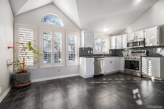 kitchen with stainless steel appliances, lofted ceiling, and white cabinets