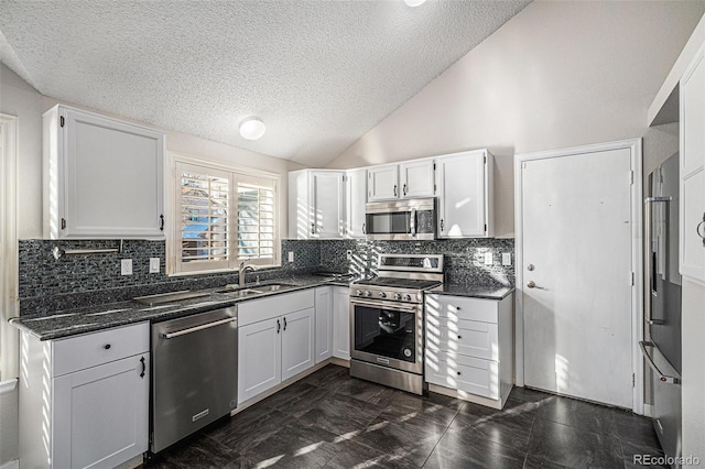 kitchen with stainless steel appliances, white cabinetry, vaulted ceiling, and sink