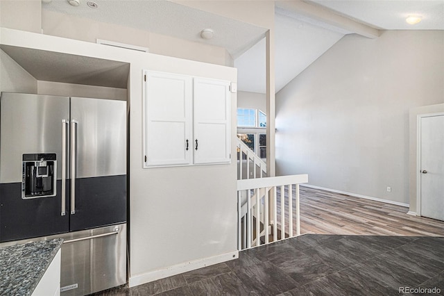 kitchen with white cabinetry, high end refrigerator, lofted ceiling with beams, and dark stone counters