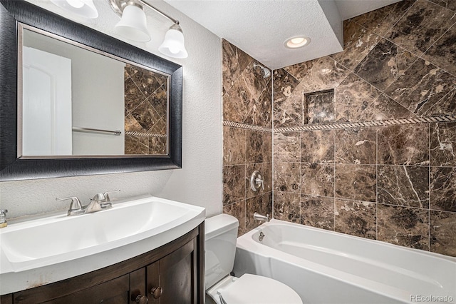 full bathroom with tiled shower / bath, vanity, a textured ceiling, and toilet