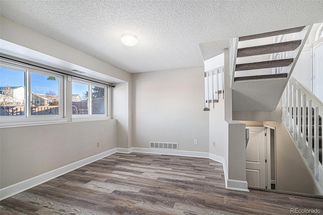 unfurnished room with hardwood / wood-style flooring and a textured ceiling