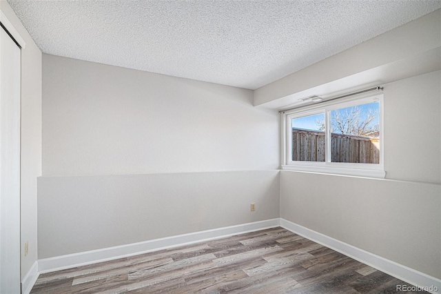 spare room featuring light hardwood / wood-style floors and a textured ceiling