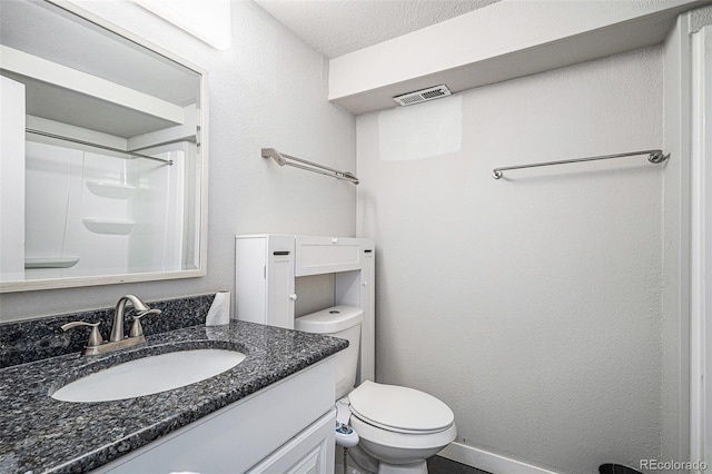 bathroom featuring a shower, vanity, a textured ceiling, and toilet