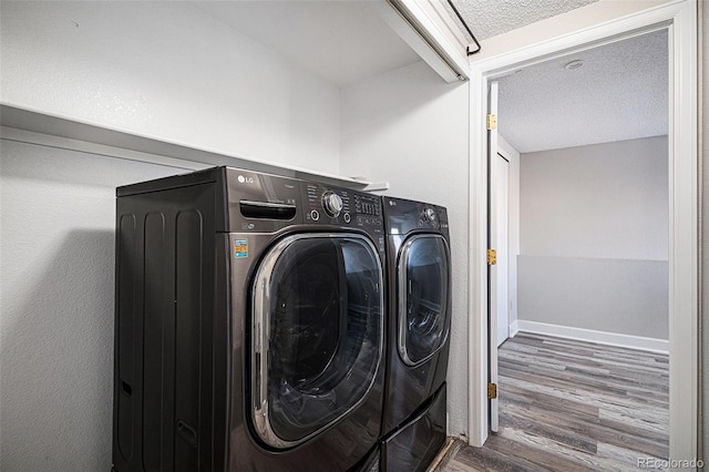 clothes washing area featuring hardwood / wood-style flooring, washing machine and dryer, and a textured ceiling