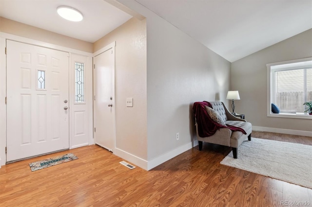 foyer entrance with wood-type flooring and vaulted ceiling