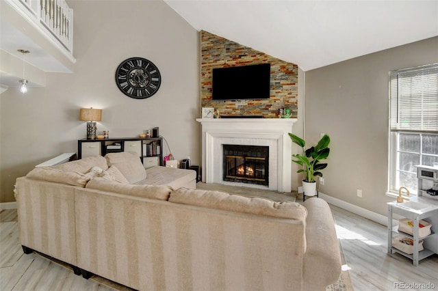 living room with a large fireplace, light hardwood / wood-style floors, and lofted ceiling