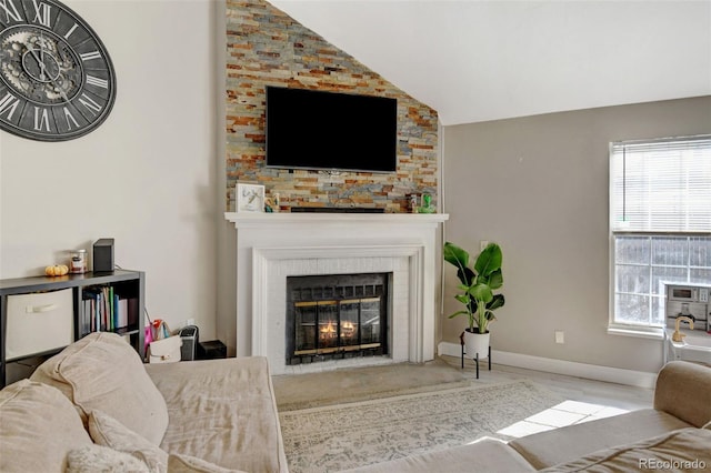 living room with a large fireplace, plenty of natural light, and lofted ceiling