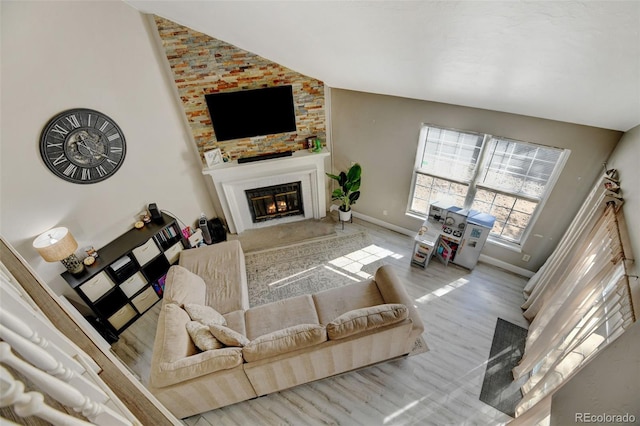 living room with light wood-type flooring, a fireplace, and high vaulted ceiling