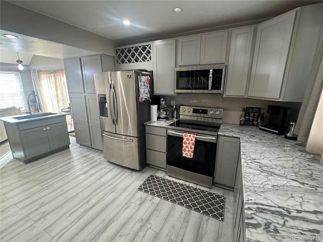 kitchen featuring appliances with stainless steel finishes, light hardwood / wood-style floors, gray cabinetry, and sink