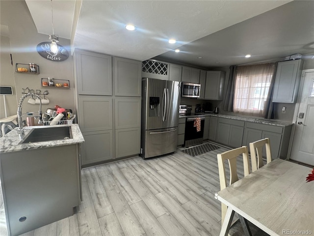 kitchen featuring hanging light fixtures, gray cabinets, sink, and appliances with stainless steel finishes