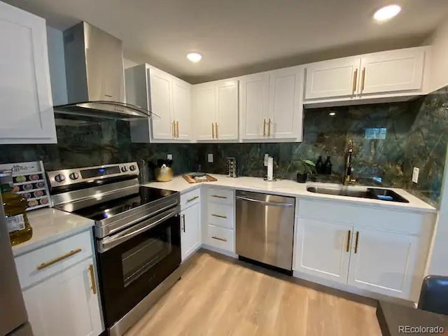 kitchen featuring appliances with stainless steel finishes, wall chimney range hood, and white cabinets