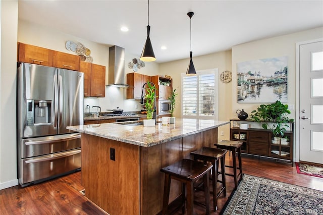 kitchen with dark wood-style flooring, brown cabinets, stainless steel refrigerator with ice dispenser, and wall chimney exhaust hood